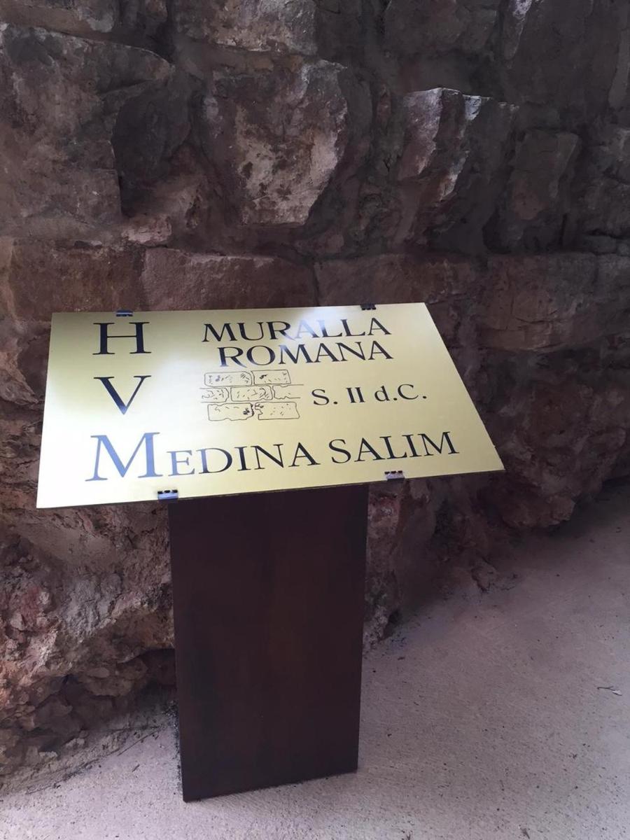 un cartel en un stand frente a una pared de piedra en Hotel MedinaSalim, en Medinaceli