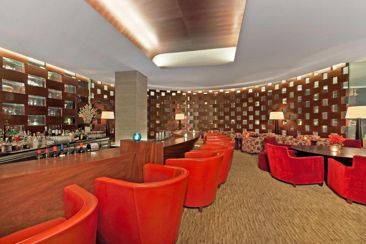 a restaurant with red chairs and a bar at The Westin Gurgaon, New Delhi in Gurgaon