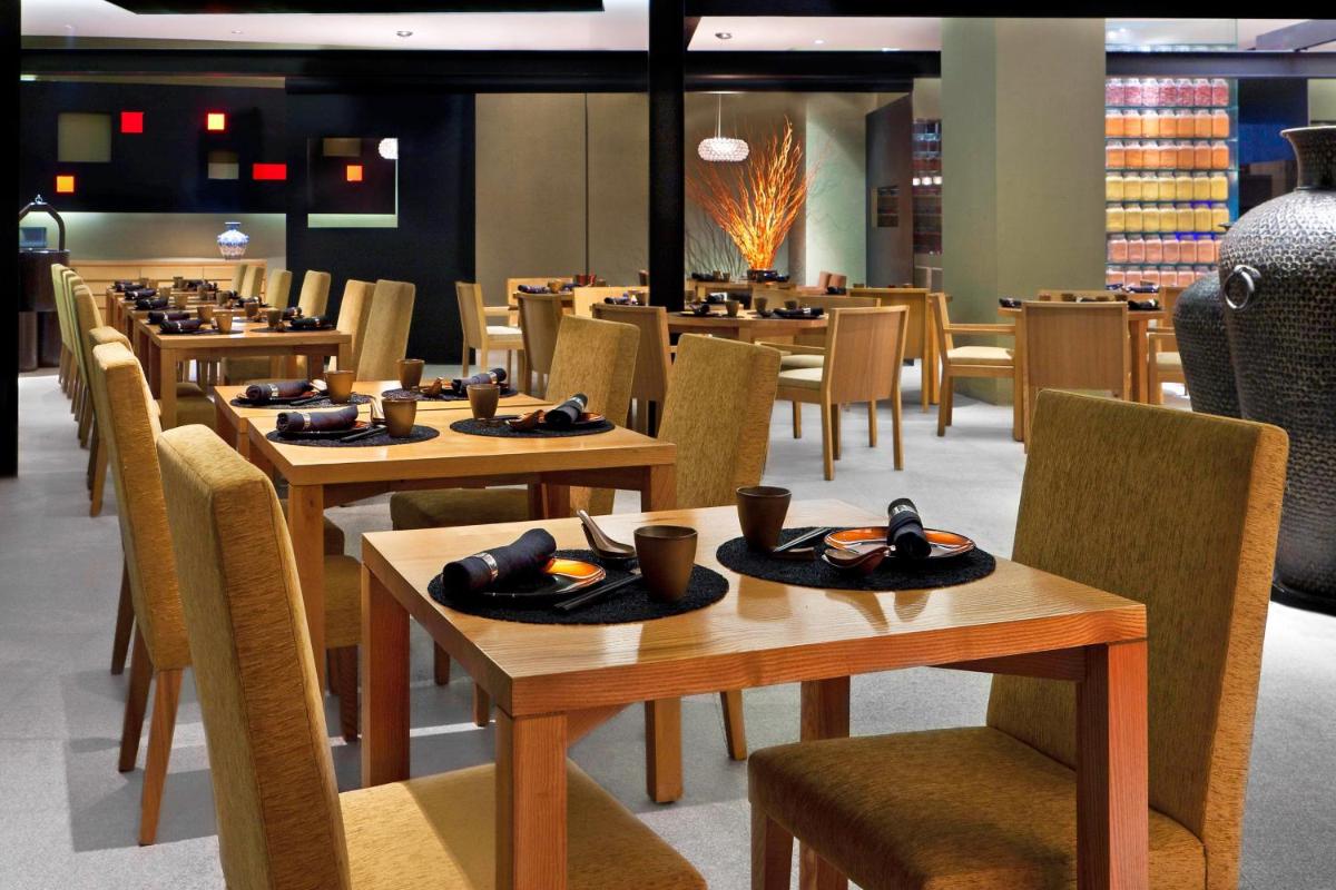 a dining room with wooden tables and chairs at The Westin Gurgaon, New Delhi in Gurgaon