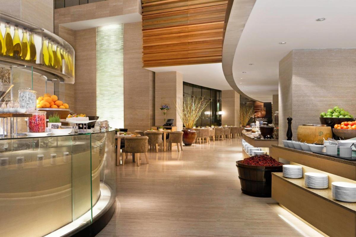 a restaurant with a buffet line with tables and chairs at The Westin Gurgaon, New Delhi in Gurgaon