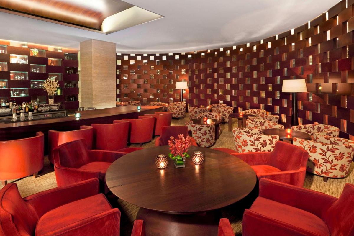 a restaurant with red chairs and a table and a bar at The Westin Gurgaon, New Delhi in Gurgaon