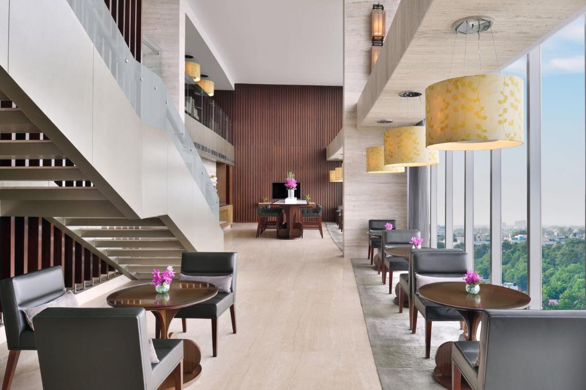 a restaurant with tables and chairs and a staircase at The Westin Gurgaon, New Delhi in Gurgaon