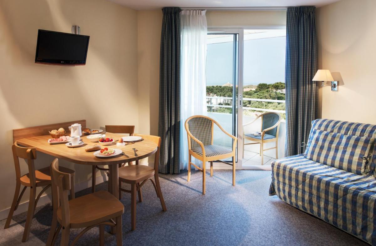 une chambre d'hôtel avec une table et un canapé dans l'établissement Résidence Valdys Thalasso & Spa - les Pins, à Saint-Jean-de-Monts