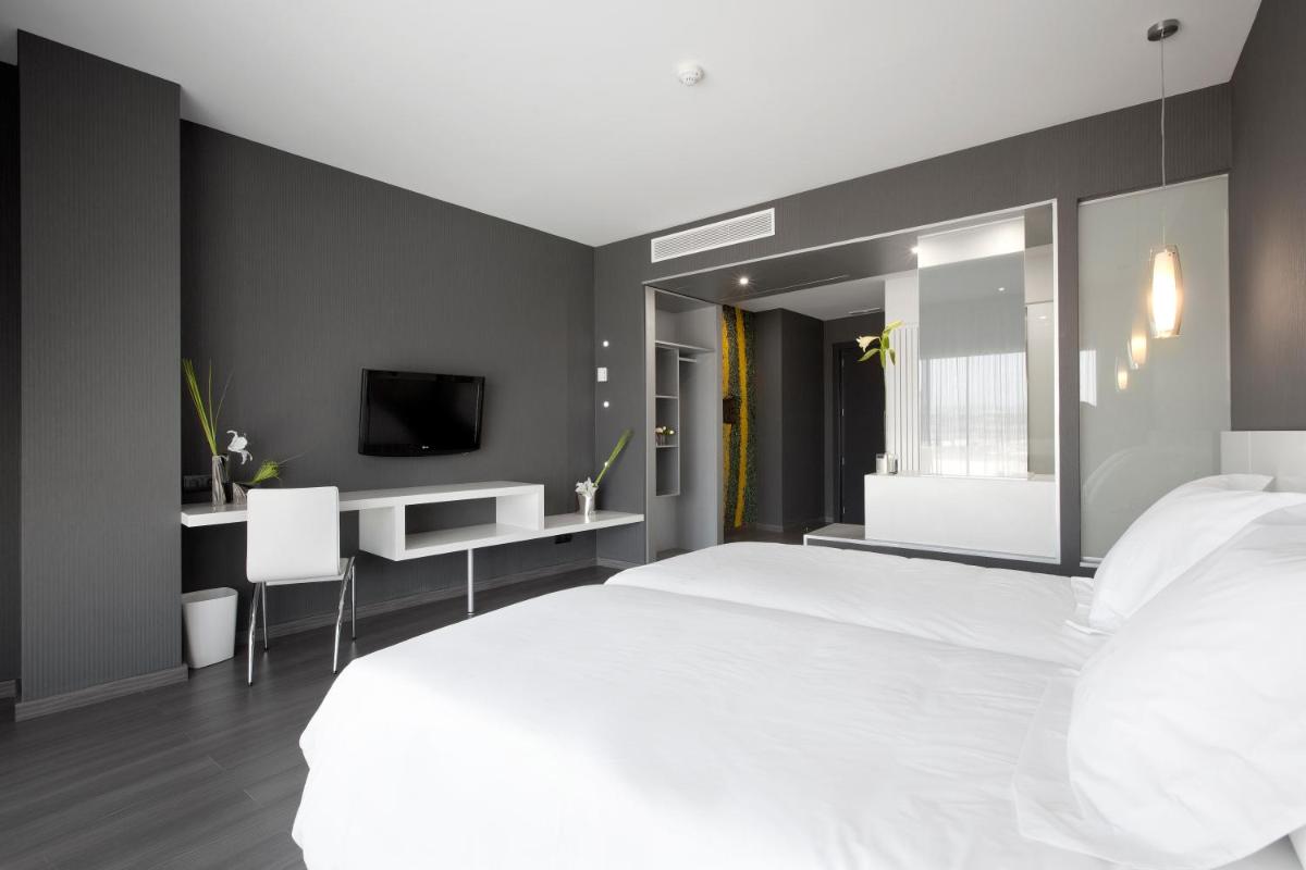 Un dormitorio con una gran cama blanca y un escritorio. en Hotel MasMonzon, en Monzón
