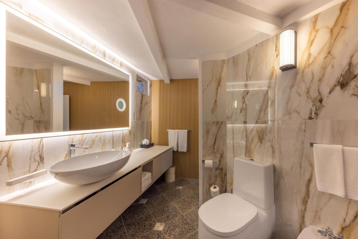 une salle de bain avec un lavabo, des toilettes et un miroir dans l'établissement Hotel & SPA des Pecheurs, à Bonifacio