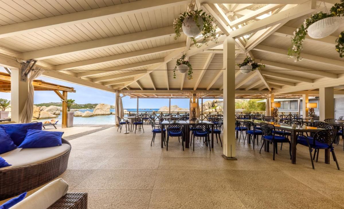 un restaurant avec des tables et des chaises et l'océan dans l'établissement Hotel & SPA des Pecheurs, à Bonifacio