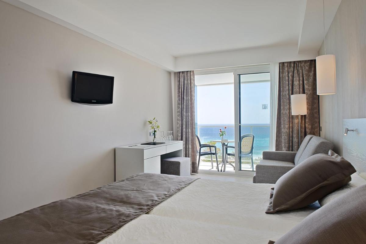 Una habitación de hotel con una cama y vista al océano. en Hipotels Hipocampo - Adults Only, en Cala Millor