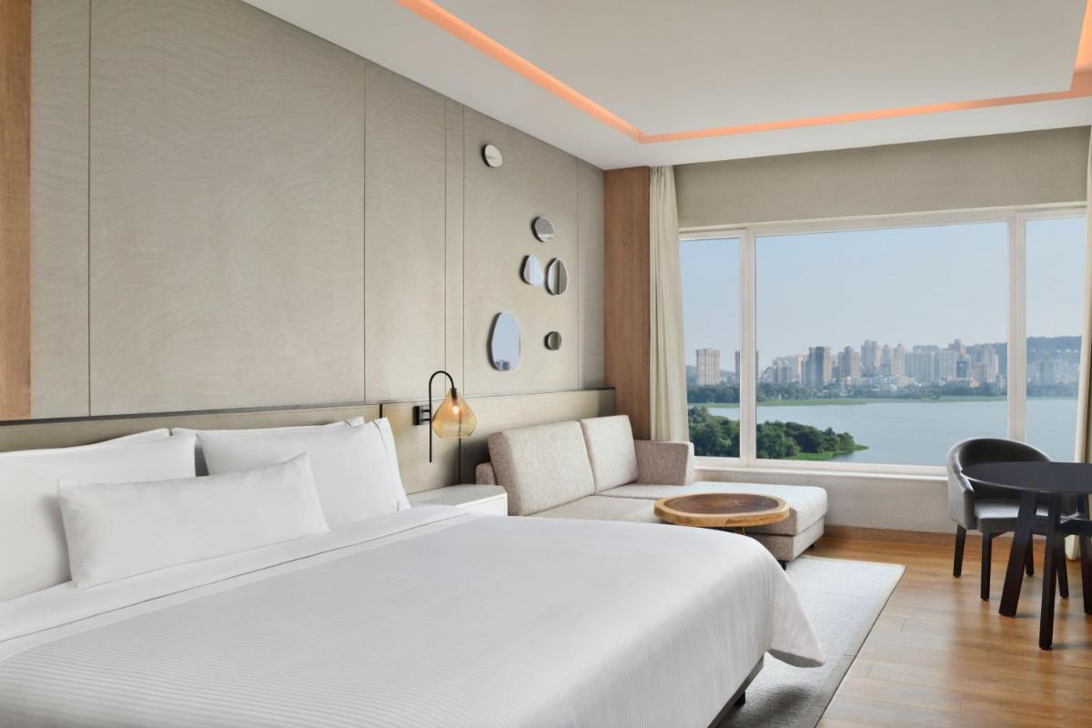 a hotel room with a large bed and a large window at The Westin Mumbai Powai Lake in Mumbai