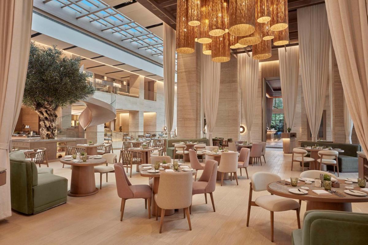 a restaurant with tables and chairs and chandeliers at Hilton Gurugram Baani City Centre in Gurgaon