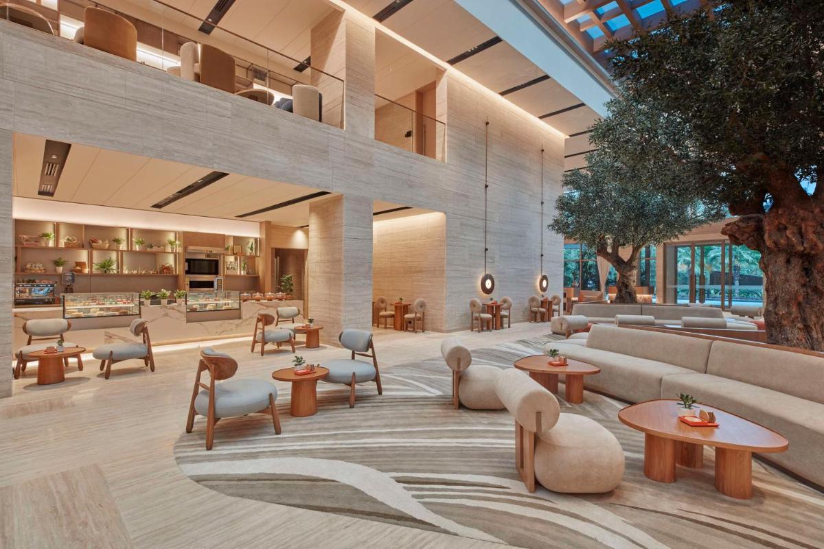 a lobby with tables and chairs in a building at Hilton Gurugram Baani City Centre in Gurgaon