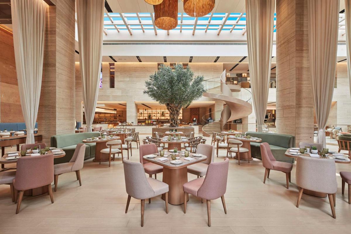 a restaurant with tables and chairs and a staircase at Hilton Gurugram Baani City Centre in Gurgaon