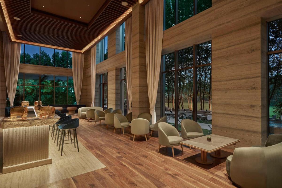 a lobby with chairs and tables and large windows at Hilton Gurugram Baani City Centre in Gurgaon