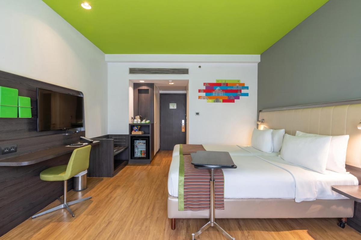 a bedroom with a bed and a desk and a tv at Park Inn by Radisson,South Delhi in New Delhi a bedroom with a bed and a desk and a tv at Park Inn by Radisson,South Delhi in New Delhi