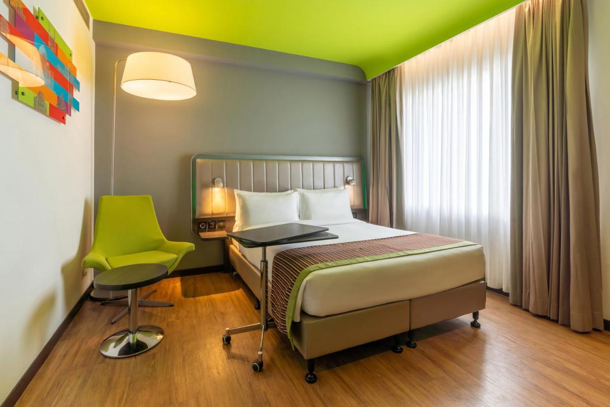 a bedroom with a bed and a green chair at Park Inn by Radisson,South Delhi in New Delhi a bedroom with a bed and a green chair at Park Inn by Radisson,South Delhi in New Delhi