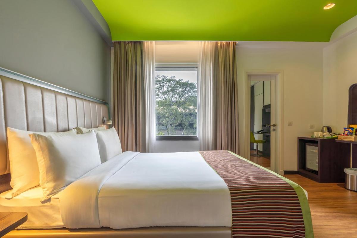 a bedroom with a large white bed and a window at Park Inn by Radisson,South Delhi in New Delhi a bedroom with a large white bed and a window at Park Inn by Radisson,South Delhi in New Delhi