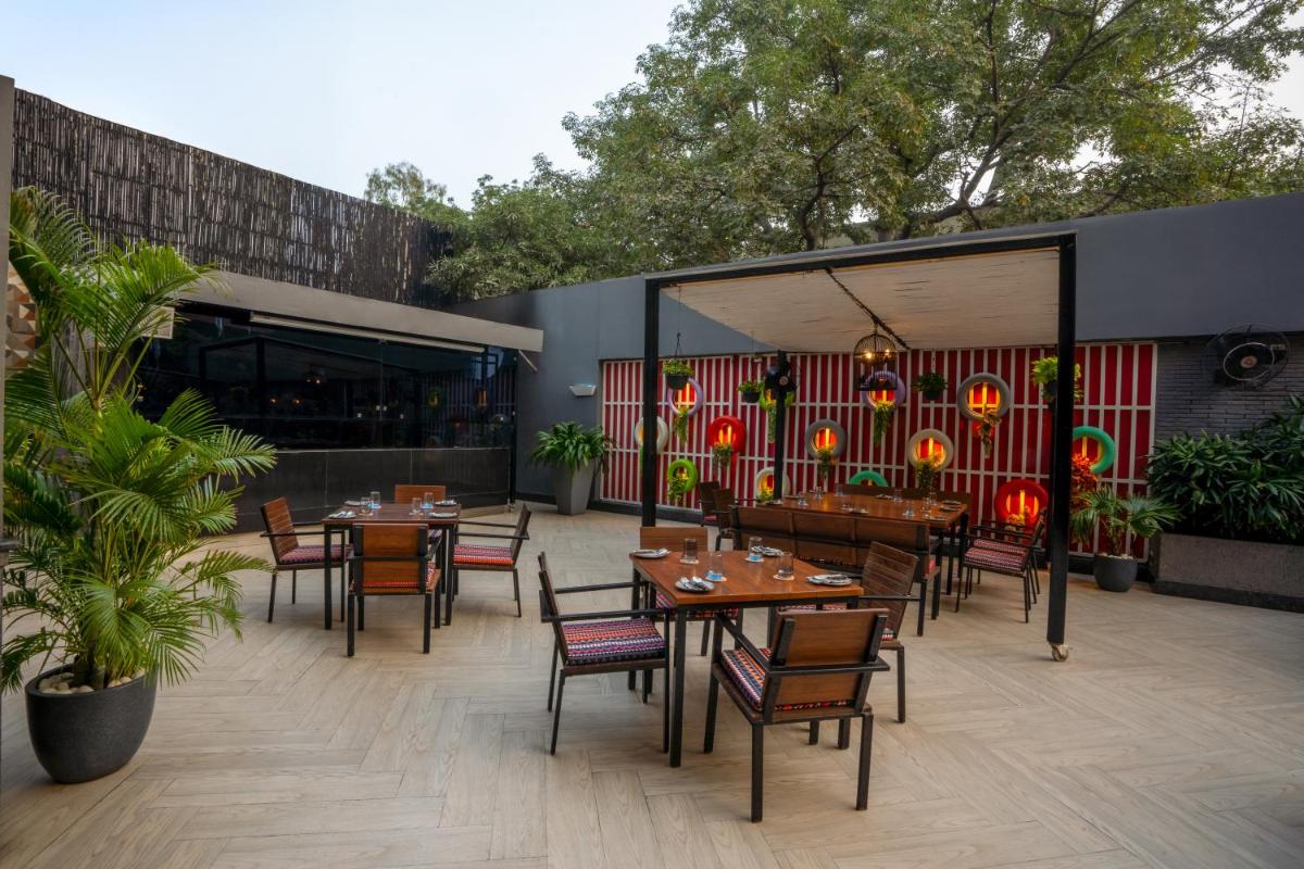 a patio with tables and chairs and a restaurant at Park Inn by Radisson,South Delhi in New Delhi a patio with tables and chairs and a restaurant at Park Inn by Radisson,South Delhi in New Delhi