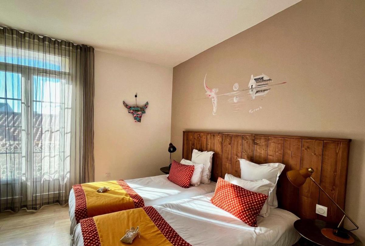 une chambre avec deux lits et une fenêtre dans l'établissement Hôtel Saint Louis, à Aigues-Mortes