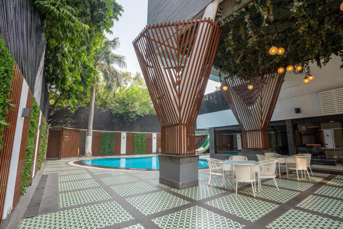 a patio with tables and chairs and a pool at Park Inn by Radisson,South Delhi in New Delhi a patio with tables and chairs and a pool at Park Inn by Radisson,South Delhi in New Delhi