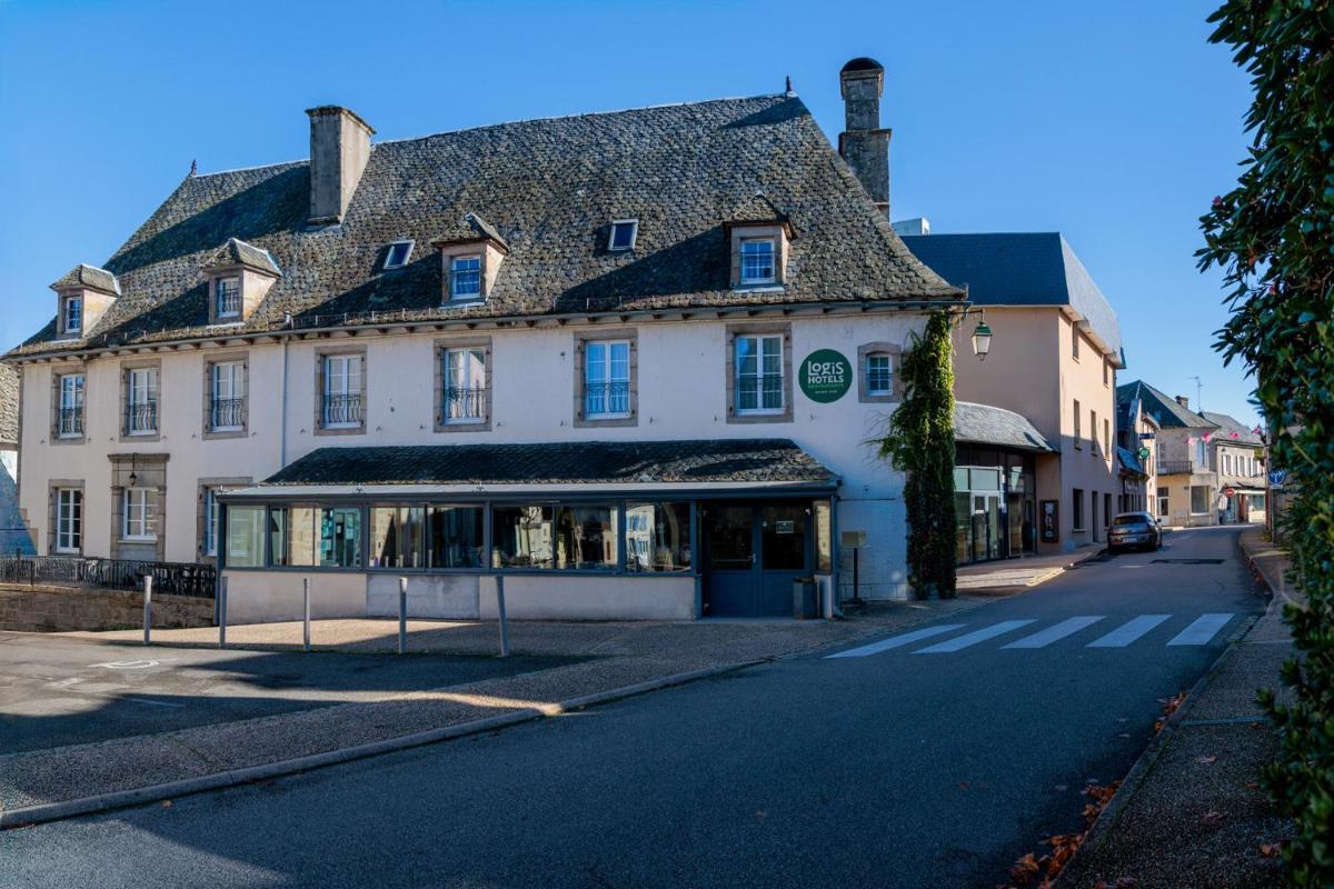 un grand bâtiment blanc au bord d'une rue dans l'établissement Logis Hôtel Restaurant Auberge de la Xaintrie, à Saint-Privat