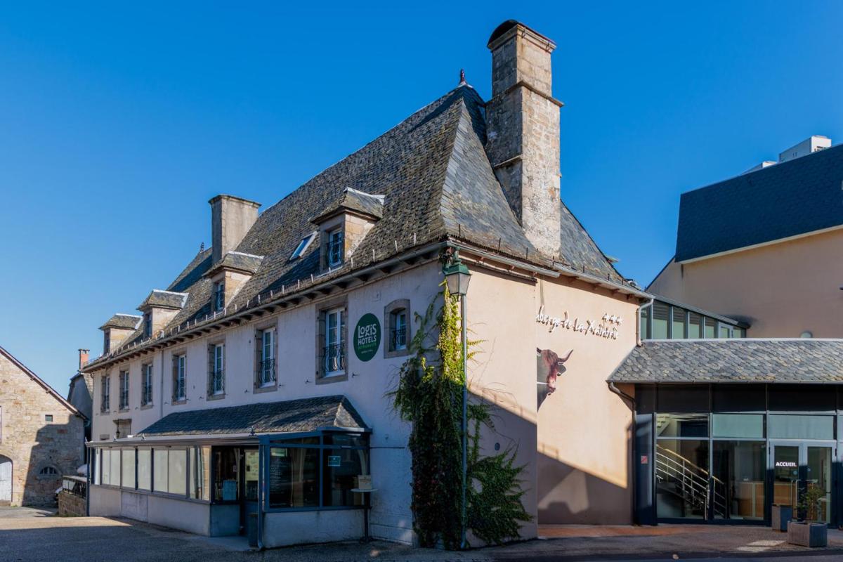 un vieux bâtiment blanc avec un toit de tuiles dans l'établissement Logis Hôtel Restaurant Auberge de la Xaintrie, à Saint-Privat