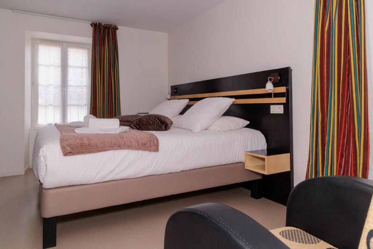 une chambre avec un grand lit aux oreillers blancs dans l'établissement Logis Hôtel Restaurant Auberge de la Xaintrie, à Saint-Privat