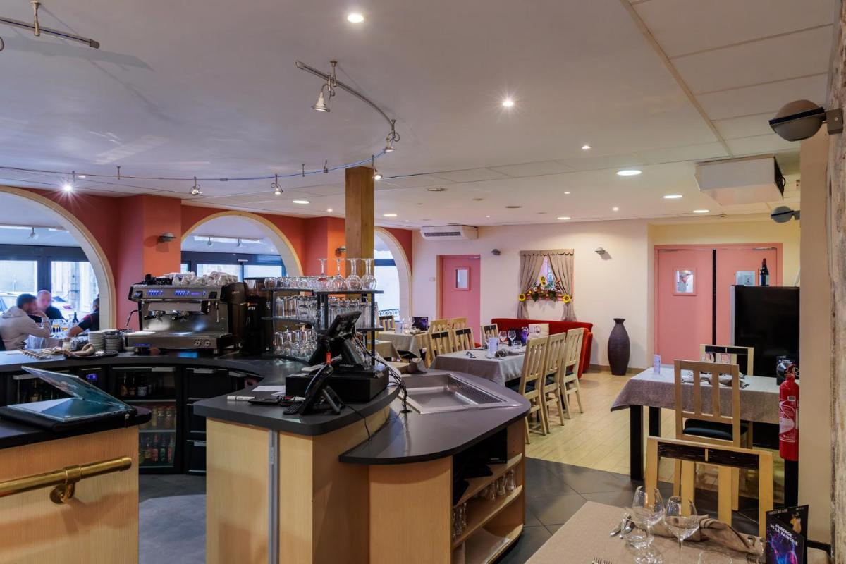 une cuisine avec des murs roses, des tables et des chaises dans l'établissement Logis Hôtel Restaurant Auberge de la Xaintrie, à Saint-Privat