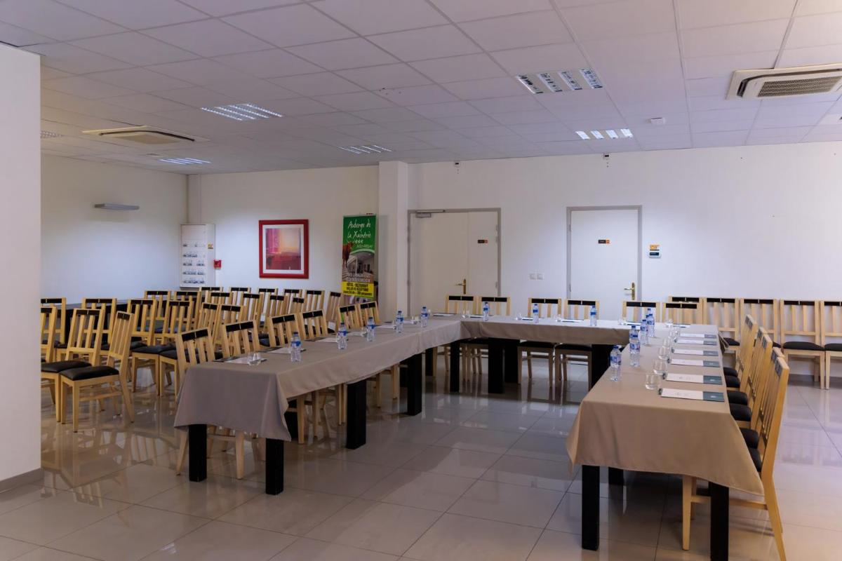 une longue table dans une pièce avec des tables et des chaises dans l'établissement Logis Hôtel Restaurant Auberge de la Xaintrie, à Saint-Privat 33 autres photos