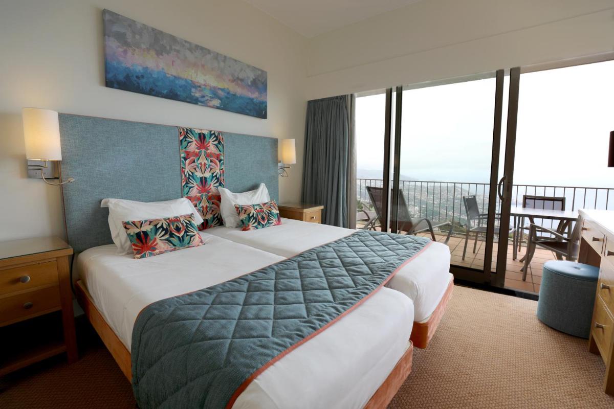 um quarto de hotel com uma cama e uma varanda em Village Cabo Girao em Câmara de Lobos