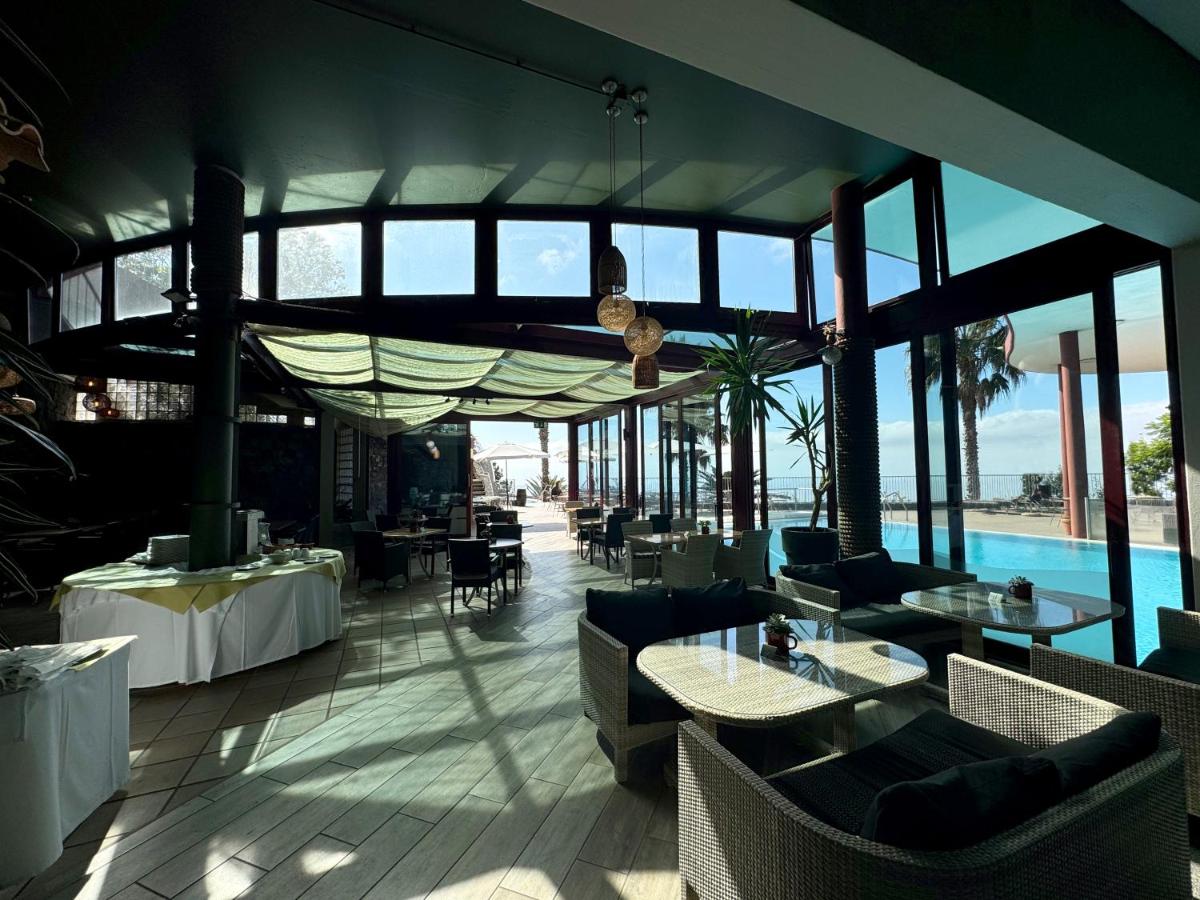 um restaurante com mesas e cadeiras e uma piscina em Village Cabo Girao em Câmara de Lobos