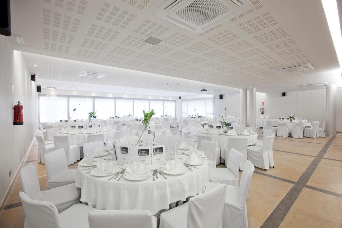 Un salón de banquetes con mesas y sillas blancas. en Hotel MasMonzon, en Monzón