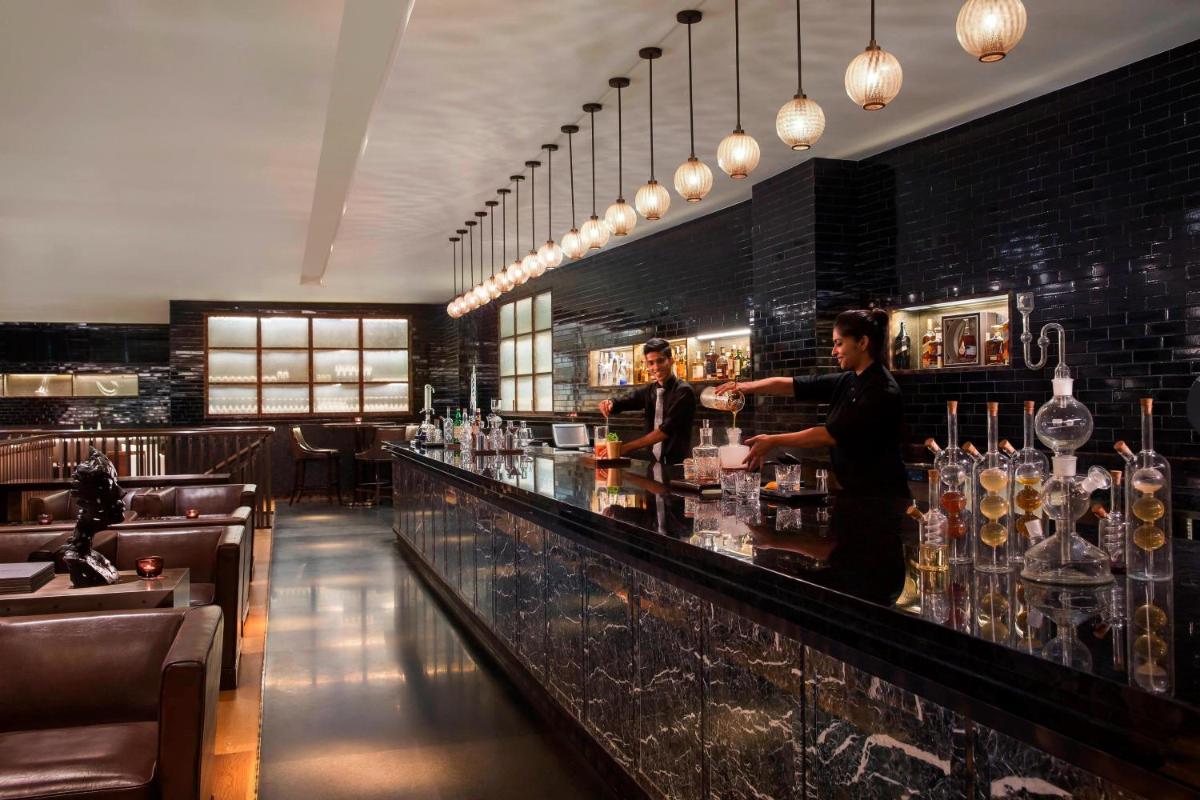 a man standing behind a bar in a restaurant at JW Marriott Mumbai Sahar Airport in Mumbai a man standing behind a bar in a restaurant at JW Marriott Mumbai Sahar Airport in Mumbai
