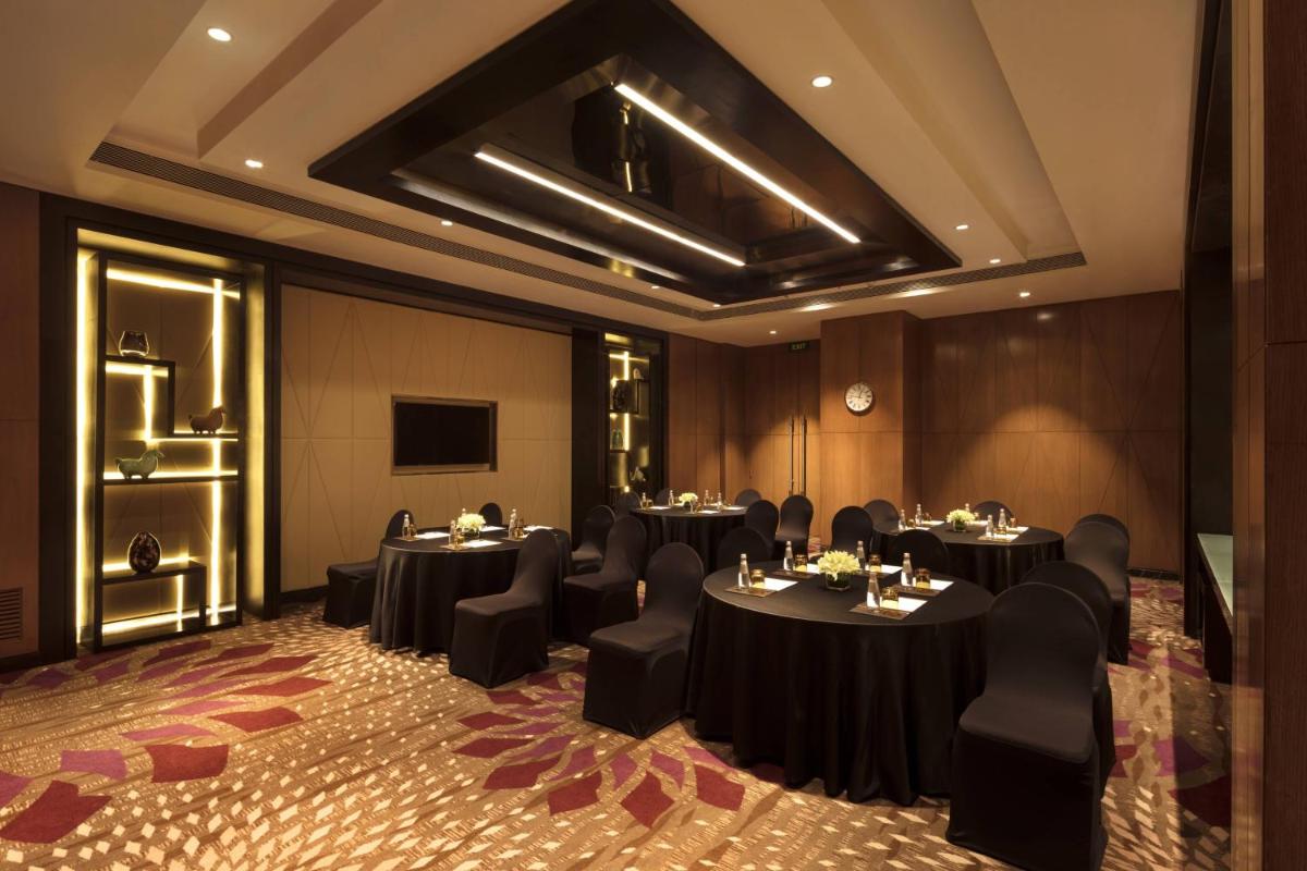 a conference room with tables and chairs and a television at JW Marriott Mumbai Sahar Airport in Mumbai a conference room with tables and chairs and a television at JW Marriott Mumbai Sahar Airport in Mumbai