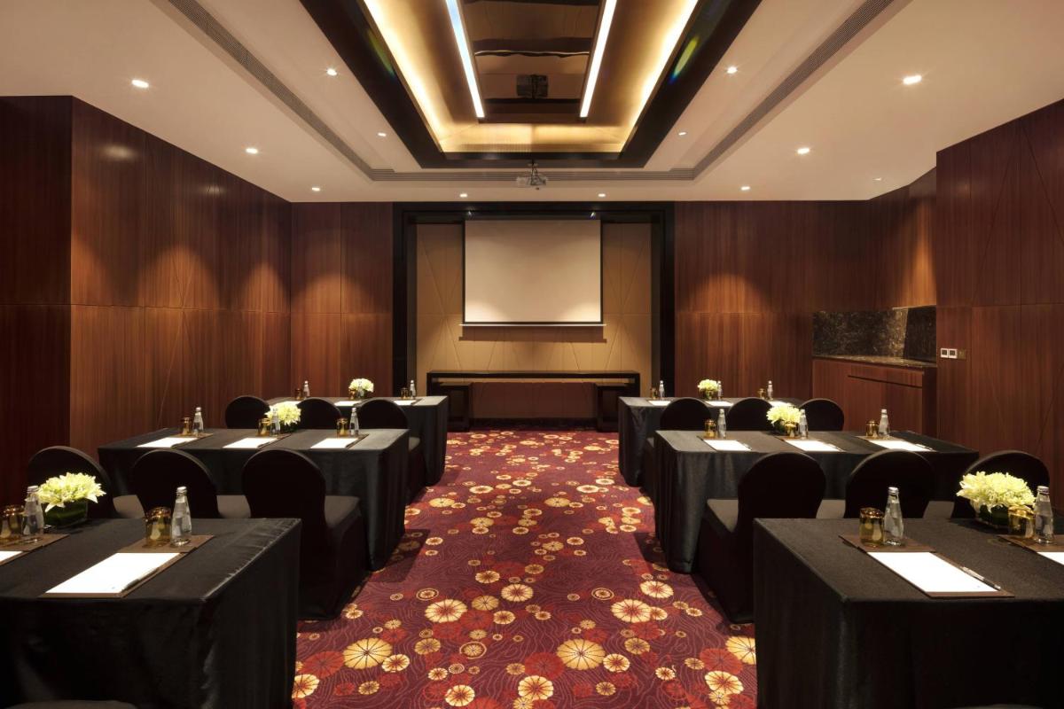 a conference room with black tables and a projection screen at JW Marriott Mumbai Sahar Airport in Mumbai a conference room with black tables and a projection screen at JW Marriott Mumbai Sahar Airport in Mumbai