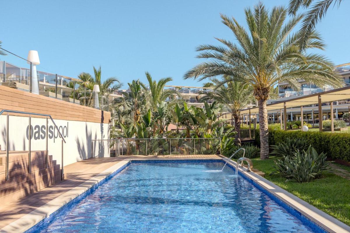 Una piscina con palmeras y un edificio. en Zafiro Palace Palmanova, en Palmanova