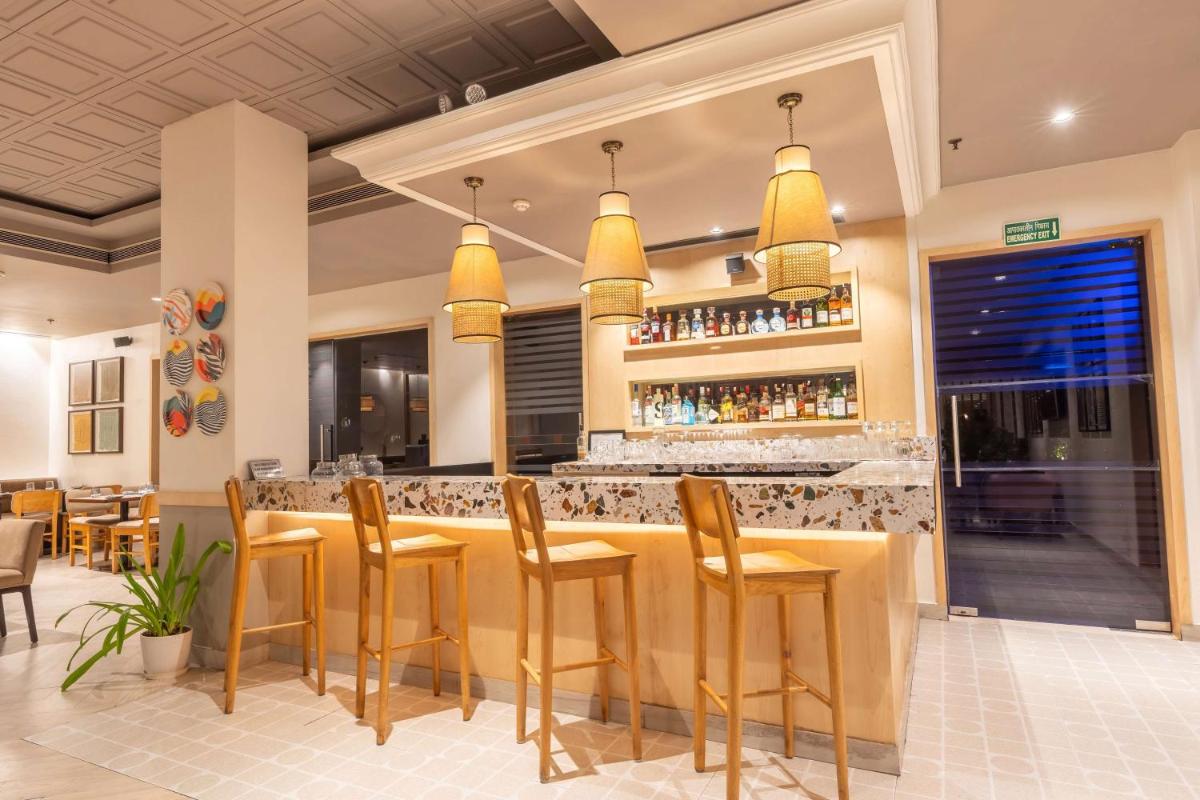 a restaurant with a bar with yellow stools at Park Inn by Radisson,South Delhi in New Delhi a restaurant with a bar with yellow stools at Park Inn by Radisson,South Delhi in New Delhi