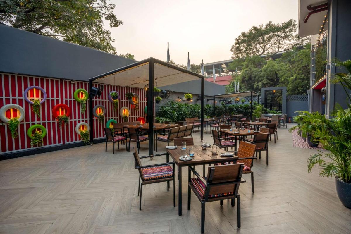 a restaurant with tables and chairs on a patio at Park Inn by Radisson,South Delhi in New Delhi a restaurant with tables and chairs on a patio at Park Inn by Radisson,South Delhi in New Delhi