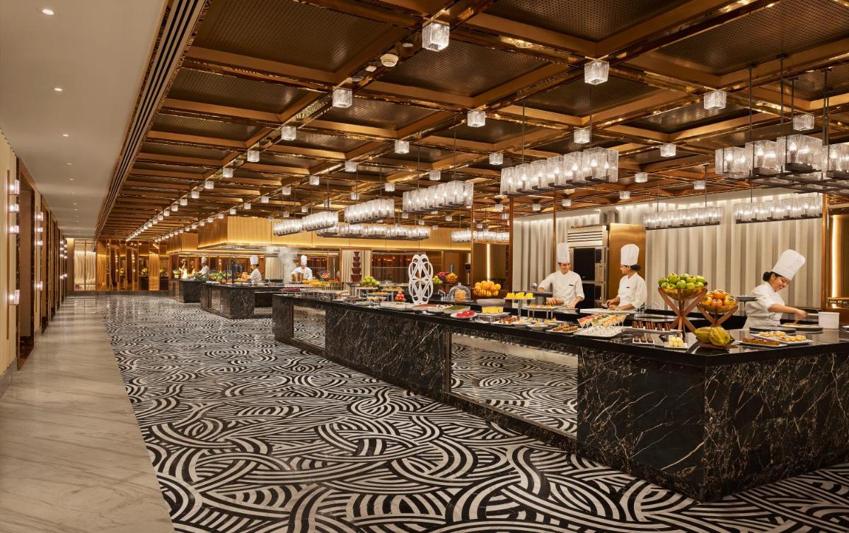 a restaurant with a buffet line with chefs preparing food at Grand Hyatt Mumbai Hotel and Residences in Mumbai