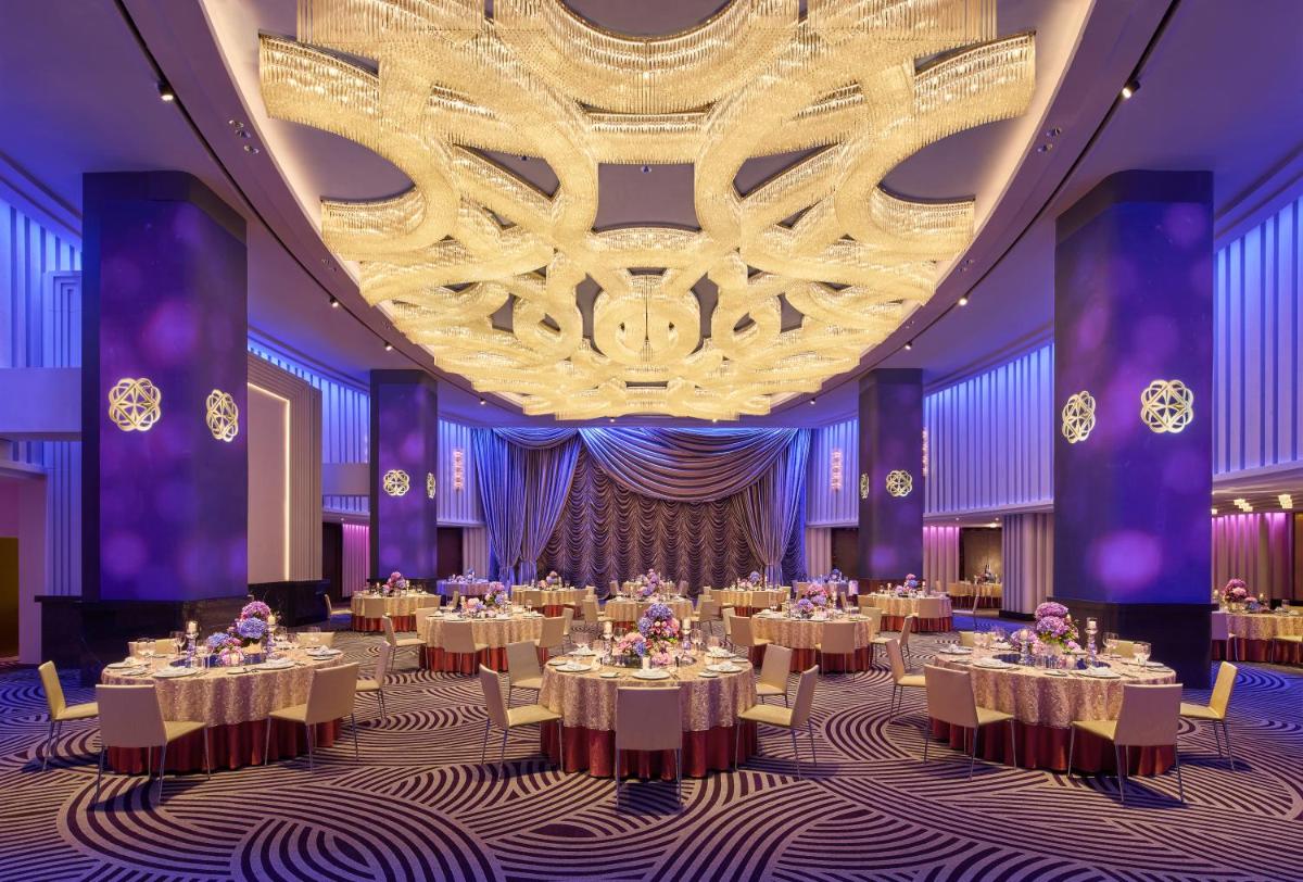 a ballroom with tables and a large chandelier at Grand Hyatt Mumbai Hotel and Residences in Mumbai