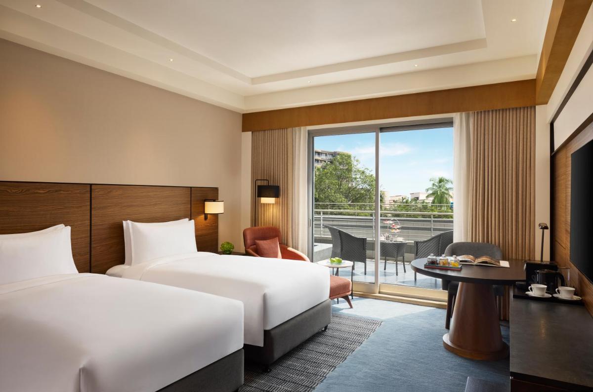 a hotel room with two beds and a balcony at Grand Hyatt Mumbai Hotel and Residences in Mumbai