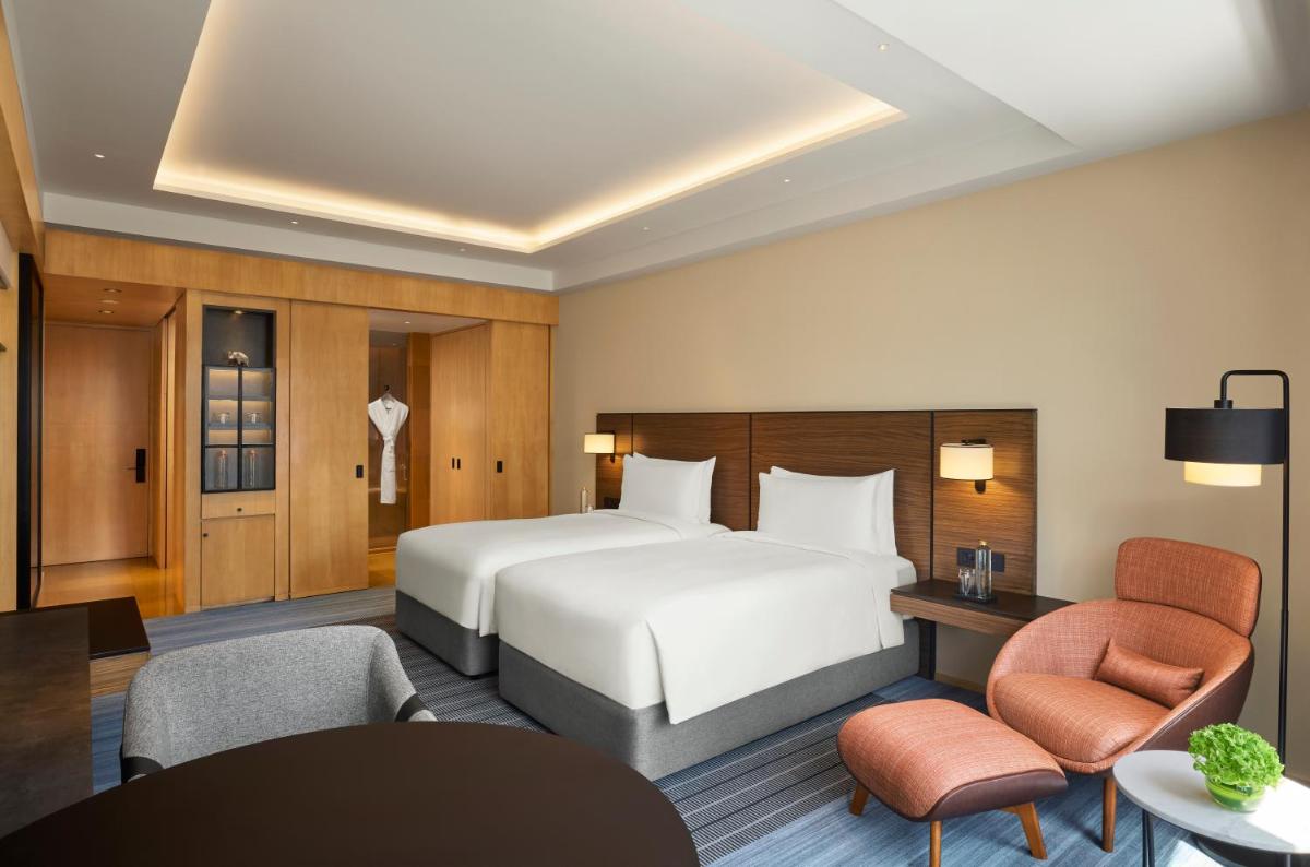 a hotel room with a large bed and chairs at Grand Hyatt Mumbai Hotel and Residences in Mumbai