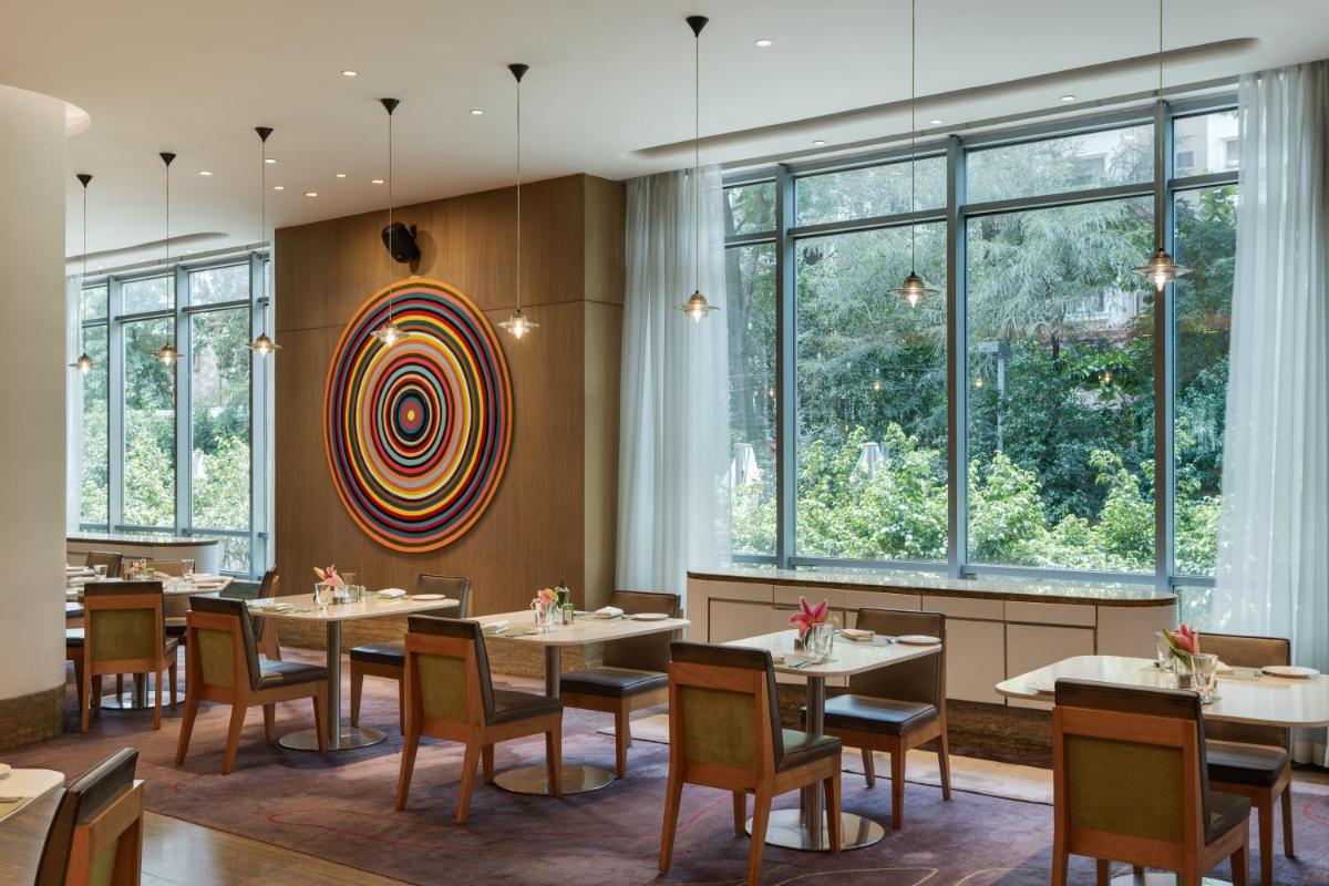 a dining room with tables and chairs and windows at Avasa Hotel in Hyderabad