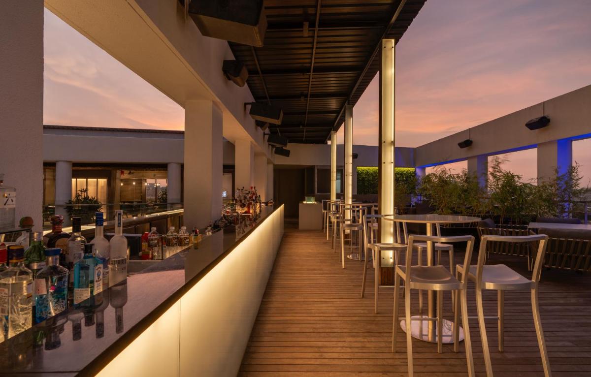 a bar on the roof of a building with tables and chairs at Avasa Hotel in Hyderabad
