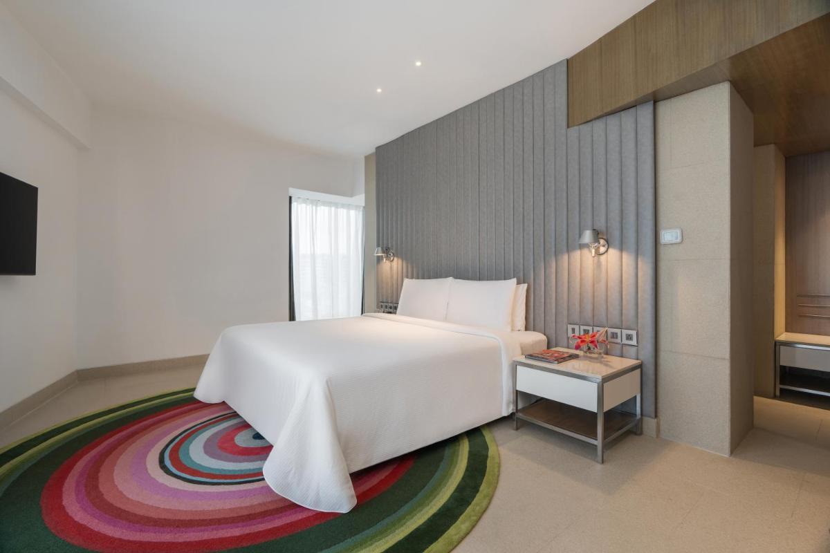 a bedroom with a white bed and a colorful carpet at Avasa Hotel in Hyderabad
