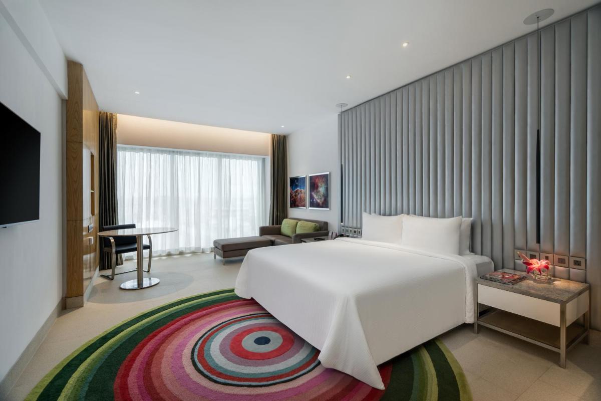 a bedroom with a large white bed and a living room at Avasa Hotel in Hyderabad