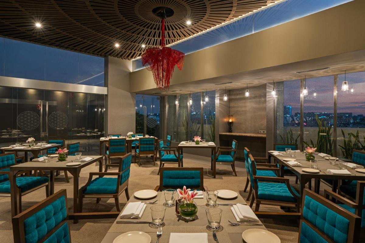 a restaurant with tables and chairs and a view of the city at Avasa Hotel in Hyderabad