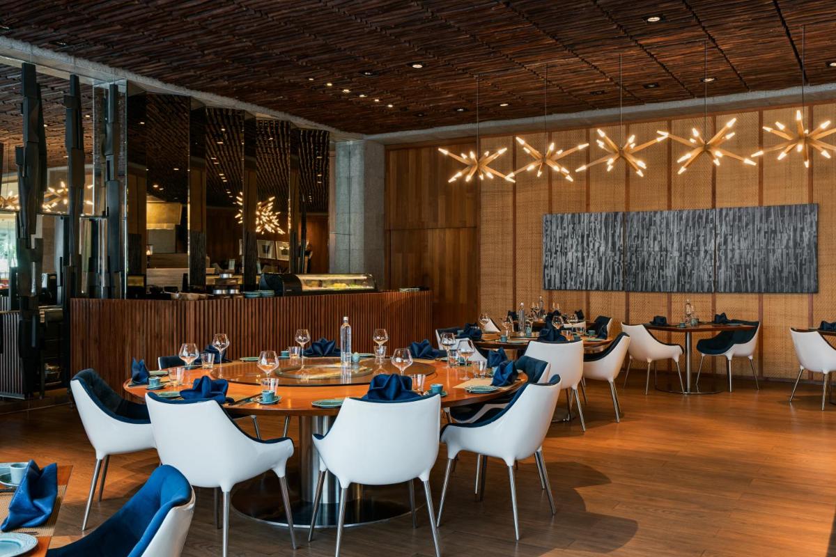 a dining room with tables and white chairs at Avasa Hotel in Hyderabad
