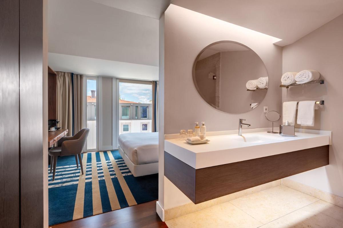 um banheiro com uma pia, uma cama e um espelho em Palácio do Governador - Lisbon Hotel & Spa em Lisboa