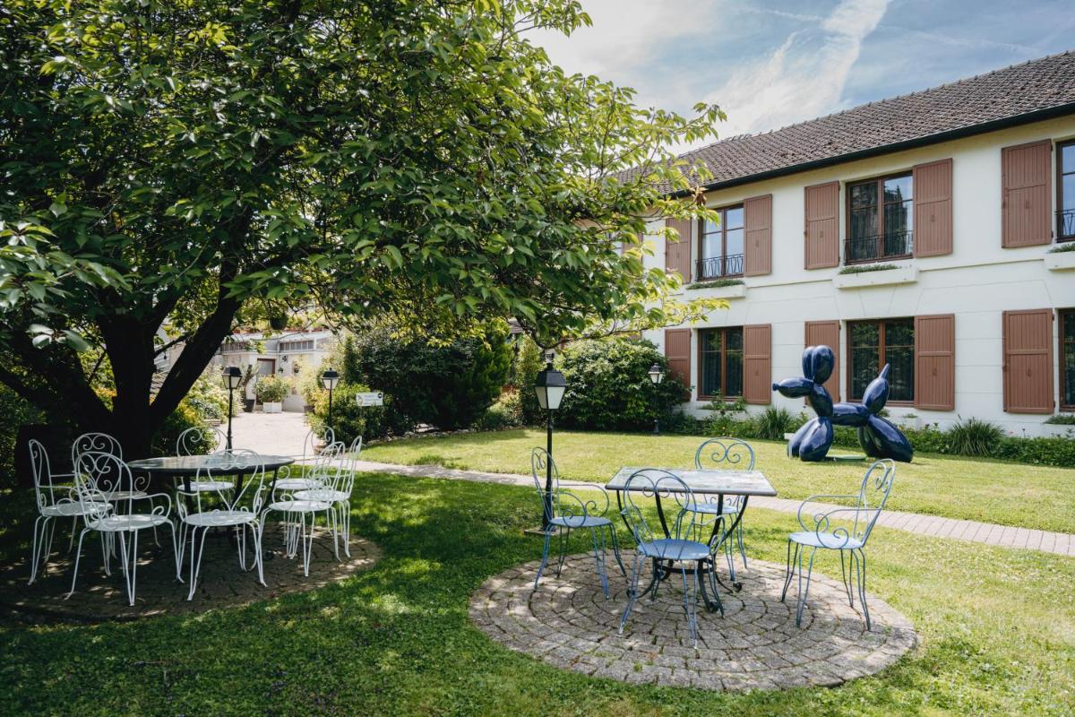 un groupe de tables et de chaises sous un arbre dans l'établissement Armes de Champagne, à Châlons-en-Champagne