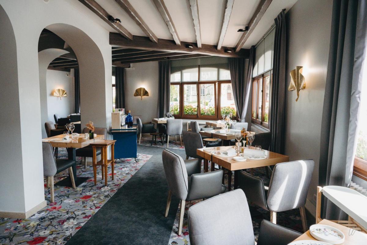 un restaurant avec des tables, des chaises et des fenêtres dans l'établissement Armes de Champagne, à Châlons-en-Champagne