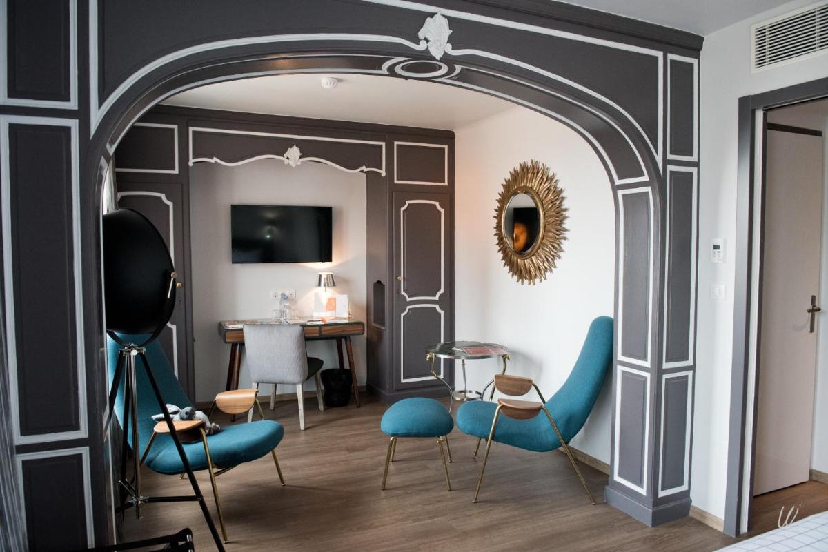 Cette chambre comprend une table et des chaises bleues. dans l'établissement Armes de Champagne, à Châlons-en-Champagne